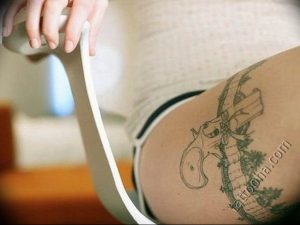 Фото тату пистолета, выполненного в минималистичном стиле на бедре. Тонкие линии и отсутствие заливки создают легкий и воздушный образ.