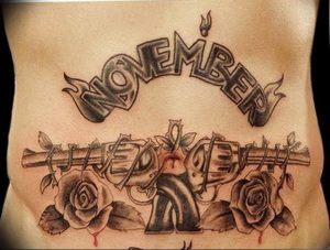 Фото тату на животе с изображением роз, колючей проволоки и надписи 'NOVEMBER' в готическом стиле.