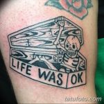 Фото тату на предплечье: простой рисунок гроба со скелетом и надписью "Life Was OK", выполненный в черно-белой гамме.