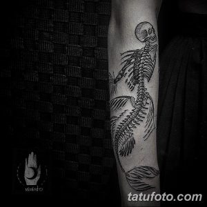 Фото тату русалки-скелета на руке. Черно-белый рисунок в стиле blackwork с использованием плотных черных заливок и четких линий.