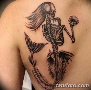 Фото тату русалки-скелета с глазом на спине в стиле blackwork. Использование черного цвета и геометрических форм.