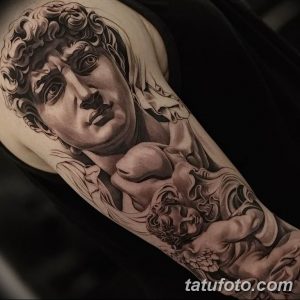 Черно-серая татуировка на руке изображает Купидона, бога любви, держащего в руках сердце, выполненная в реалистичном стиле.