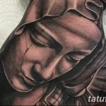 Черно-серая татуировка на руке, изображающая Богоматерь в платке, с нежным и смиренным выражением лица, выполненная в реалистичном стиле.