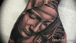 Черно-серая татуировка на руке, изображающая Богоматерь в платке, с нежным и смиренным выражением лица, выполненная в реалистичном стиле.