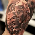 Фото тату на руке: реалистичное изображение трех человеческих лиц, выполненное в черно-серых тонах. Детализированный рисунок татуировки с акцентом на выражение лиц.