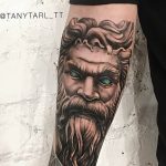 Фото тату с изображением бога Посейдона на руке. Детализированная проработка лица, бороды и волос, а также элементов морской стихии.