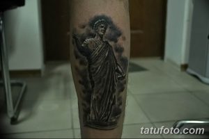 Фото тату: изображение античной статуи в одежде, выполненное в черно-серых тонах на икре ноги.