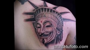 Фото тату на плече: реалистичное изображение лица в маске анонима (Guy Fawkes mask), выполненное в черно-серых тонах с акцентом на детализацию.