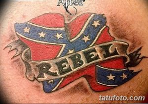 Фото тату конфедеративного флага с надписью 'Rebel'. Красные, белые и синие цвета, лента с надписью, смелый и противоречивый дизайн.