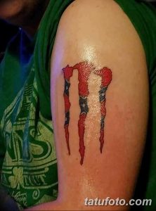 Фото тату на руке с изображением логотипа Monster Energy, выполненного в цветах американского флага. Детализированный рисунок татуировки, символизирующий энергию и страсть.