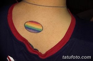 Фото минималистичной татуировки радуги на ключице девушки. Простые линии и яркие цвета.