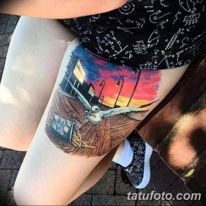 Фото тату: большая цветная татуировка чайки, летящей над ночным городом с яркими огнями на бедре.