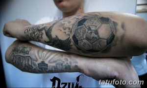 Фото татуировки в виде футбольного рукава на предплечье. Изображение футбольного мяча, города и других элементов, выполненных в черно-серой гамме.
