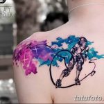 Фотография акварельной татуировки роллергейта на спине, выполненной в динамичной позе с использованием ярких цветов и брызг краски.