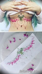Фотография акварельной татуировки с изображением цветущей ветки фуксии, расположенной на груди и животе. Нежные розовые и зеленые оттенки.
