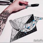 Эскиз татуировки кита, выполненный в геометрическом стиле с использованием треугольников и линий, нарисованный на бумаге. Рядом рука с маркером. Подходит для любителей морской тематики и современных дизайнов.