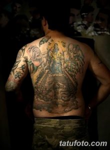 Фото тату: Большая татуировка на спине, изображающая лестницу, ведущую в небо, с ангелами и облаками. Яркие цвета и детализированная проработка.