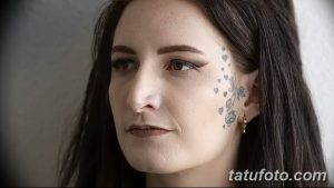 Фото тату маленьких голубых сердечек, расположенных вдоль виска и уха девушки с темными волосами. Изящный рисунок татуировки.