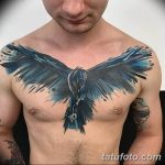 Фото тату ворона на груди мужчины. Акварельный стиль, сине-голубая цветовая гамма. Динамичный рисунок татуировки с размытыми краями.