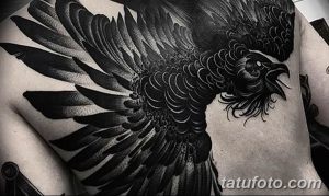 Фото тату ворона с расправленными крыльями на груди. Черно-белая татуировка, выполненная в реалистичном стиле.