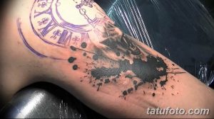 Фото тату на плече в стиле акварель, с изображением карманных часов и брызг краски. Яркий и оригинальный рисунок.