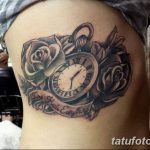 Фото тату на боку: карманные часы в окружении роз и надпись 'Time Heals Everything' в стилизованной рамке.
