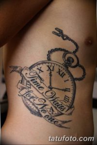Фото тату на боку с изображением карманных часов и надписи "Time waits for no one". Черно-серый рисунок с элементами декора.