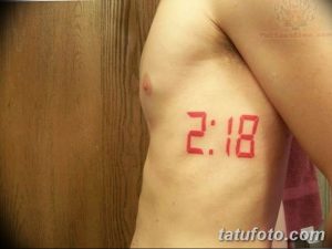 Фото татуировки на боку с красными цифровыми часами, показывающими время 2:18. Минималистичный и современный дизайн.