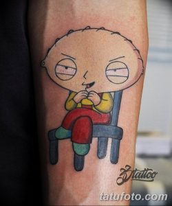 Фото тату: Цветная татуировка Stewie Griffin, персонажа мультсериала Family Guy, сидящего в кресле. Рисунок на предплечье.