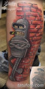 Фото тату на руке с изображением робота Бендера из мультсериала Futurama на фоне кирпичной стены. Яркий и забавный рисунок татуировки в стиле мульт.