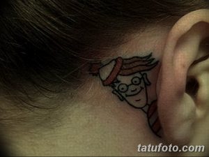 Фото миниатюрной татуировки с изображением персонажа мультфильма, расположенной за ухом, выполненное в черном цвете.