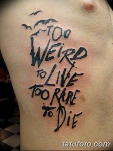 Фото татуировки на груди с надписью "Too Weird to Live, Too Rare to Die", выполненной в свободной, рукописной манере.