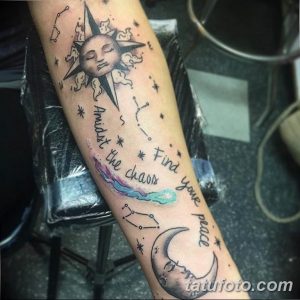 Фото тату на руке, изображающее луну, звезды, созвездия и надпись 'Amidst the chaos find your peace'. Выполнено в мягких тонах, с использованием акварельной техники.