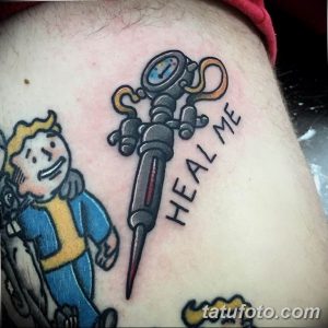 Фото тату на руке, изображающее персонажа из игры Fallout и медицинский шприц с надписью 'HEAL ME'. Выполнено в стиле олдскул, с яркими цветами и четкими контурами.