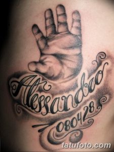 Черно-серая татуировка отпечатка детской руки с именем "Alessandro" и датой рождения "08.04.28". Сентиментальный и трогательный рисунок.