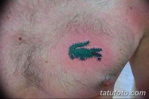 Фото минималистичной татуировки на груди, изображающей логотип Lacoste – зеленого крокодила. Небольшой и стильный рисунок.