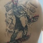 Фото тату до и после: старая, нечеткая татуировка обезьяны перекрыта детализированным изображением обезьяны с бензопилой.