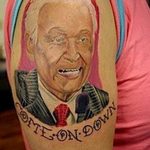 Татуировка с изображением политика и надписью "Come On Down". Рисунок в цвете, расположен на плече, детализированная проработка лица.