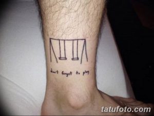 Фото тату на лодыжке: схематичное изображение качелей и надпись 'Don't forget to play'. Минималистичный черно-белый рисунок татуировки.