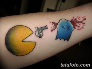 Фото тату на предплечье: Pac-Man стреляет в призрака из пистолета. Яркий и динамичный рисунок татуировки в мультяшном стиле.