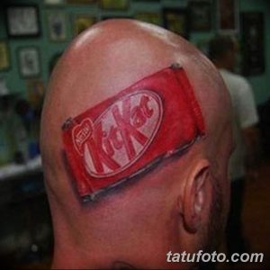 Фото тату на голове: реалистичный рисунок шоколадного батончика KitKat, словно приклеенного к лысой голове. Экстравагантная и запоминающаяся татуировка.