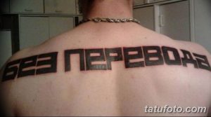 Фото татуировки на спине с надписью 'Без Перевода' выполненной черным цветом. Простой и лаконичный рисунок татуировки.