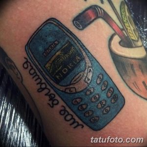 Фото тату с изображением старого телефона Nokia, выполненное в ярких, но немного выцветших цветах. Ностальгический и оригинальный выбор для поклонников 90-х.