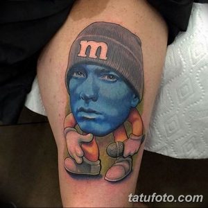 Фото тату с изображением Эминема в виде конфеты M&M's, выполненное в ярких, насыщенных цветах. Оригинальный и юмористический выбор.