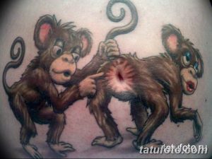 Фото татуировки на плече с изображением двух обезьян, одна из которых дергает другую за хвост. Цветной рисунок татуировки в мультяшном стиле.