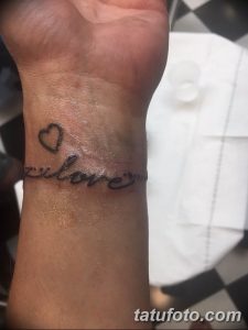 Фото тату надписи "love" и маленького сердечка на запястье. Черный цвет, тонкие линии.