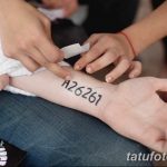 Фото процесса нанесения татуировки: мастер переносит трафарет с числовым кодом на руку клиента.