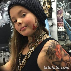 Фотография молодой девушки с татуировками бабочек и цветов на шее, руках и плечах. Татуировки выполнены в ярких цветах.