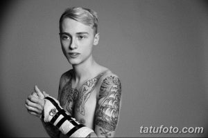 Фотография молодого человека с татуировками на руках и груди, демонстрирующая современный стиль и индивидуальность.