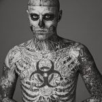 Фотография мужчины, полностью покрытого сложными татуировками в стиле биомеханика, создающими эффект механического тела.